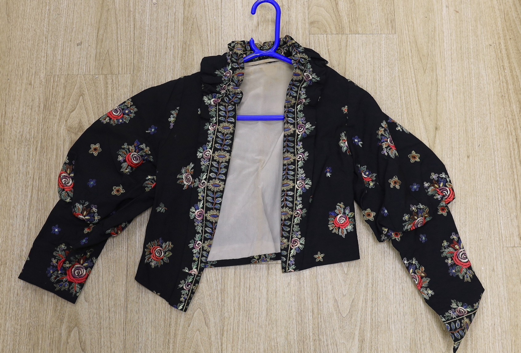 A 1930's-40's black evening jacket, embroidered with multi coloured floral embroidery, together with a blue silk velvet jacket and large bow jabot